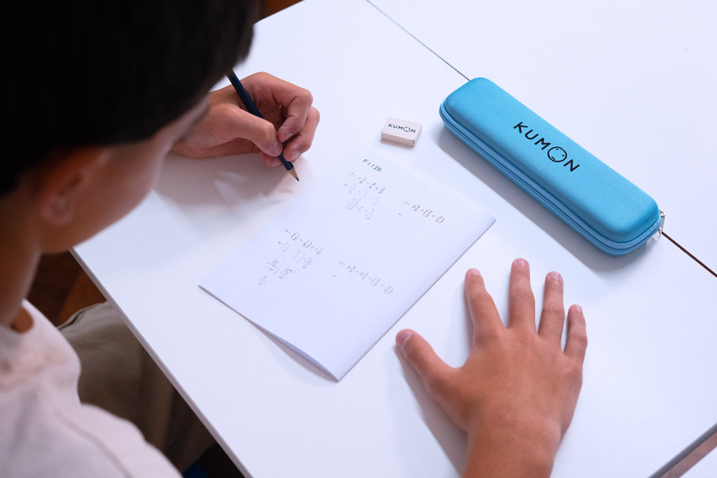 Alumno resolviendo ejercicios avanzados de matemáticas en un cuaderno Kumon, siguiendo un aprendizaje gradual y estructurado-Peru